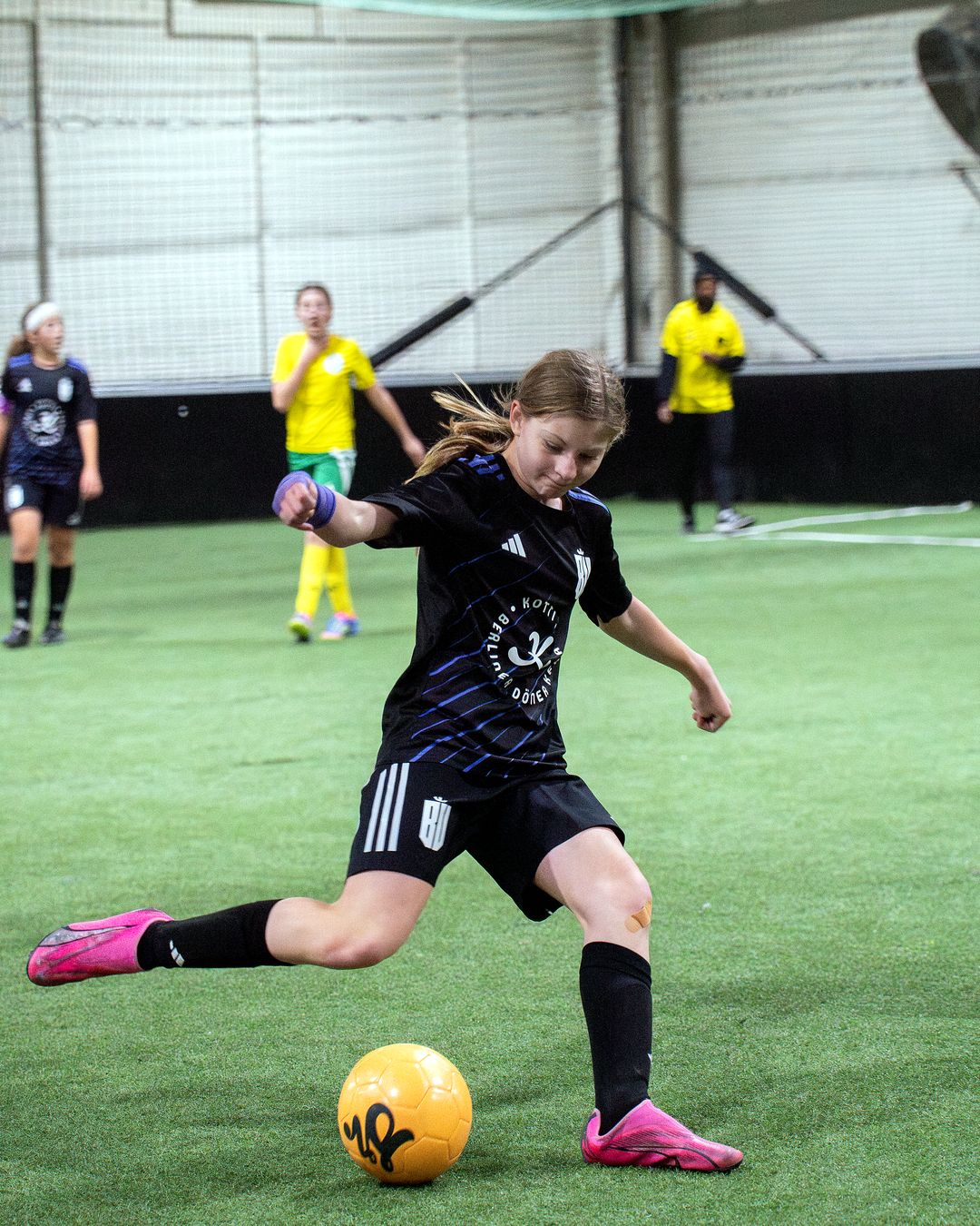 Youth soccer player striking the ball during a match on the indoor turf at Arena One.