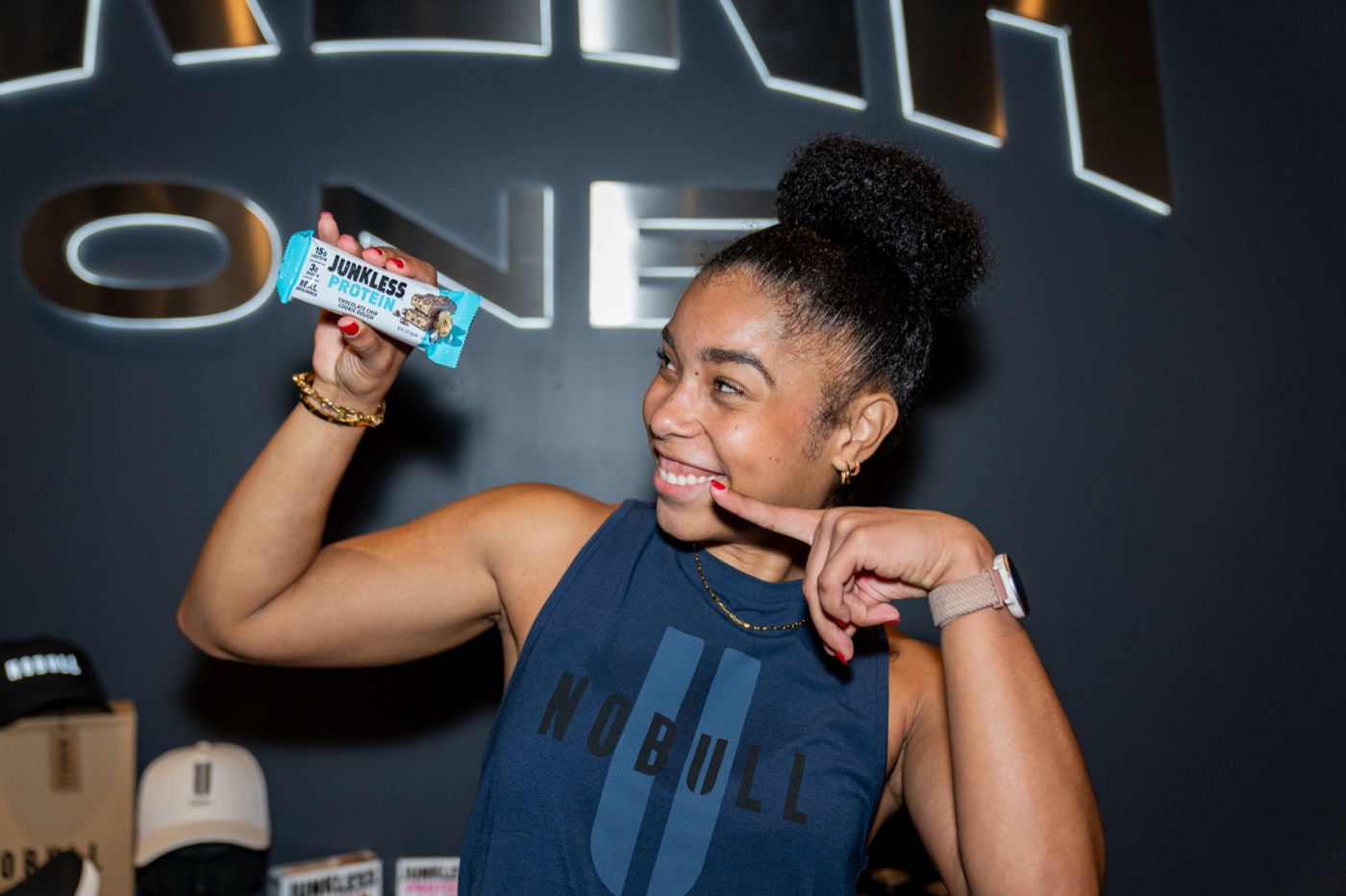 A League member holding a protein bar in front of the venue signage.