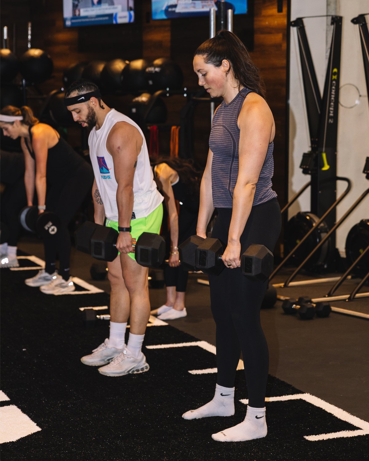A coached group class working through a strength circuit.